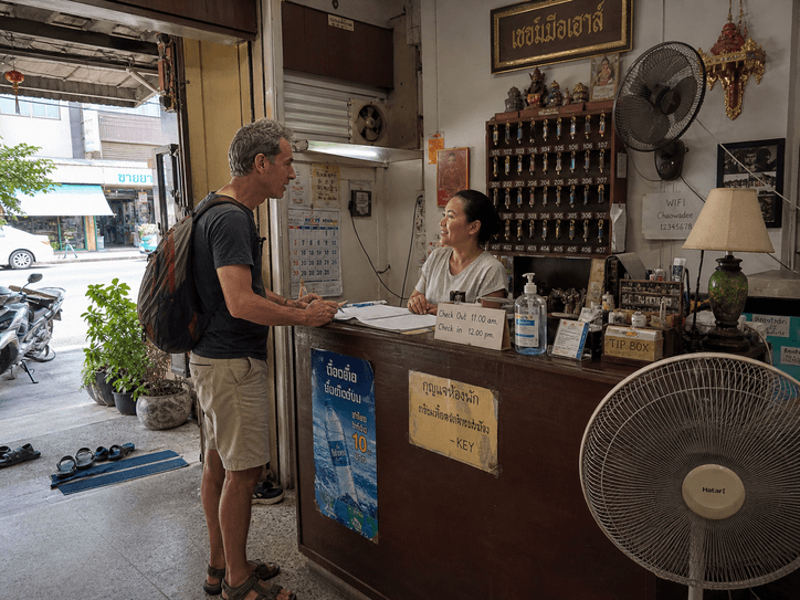 Un touriste échange avec une réceptionniste dans une petite réception en Thaïlande.